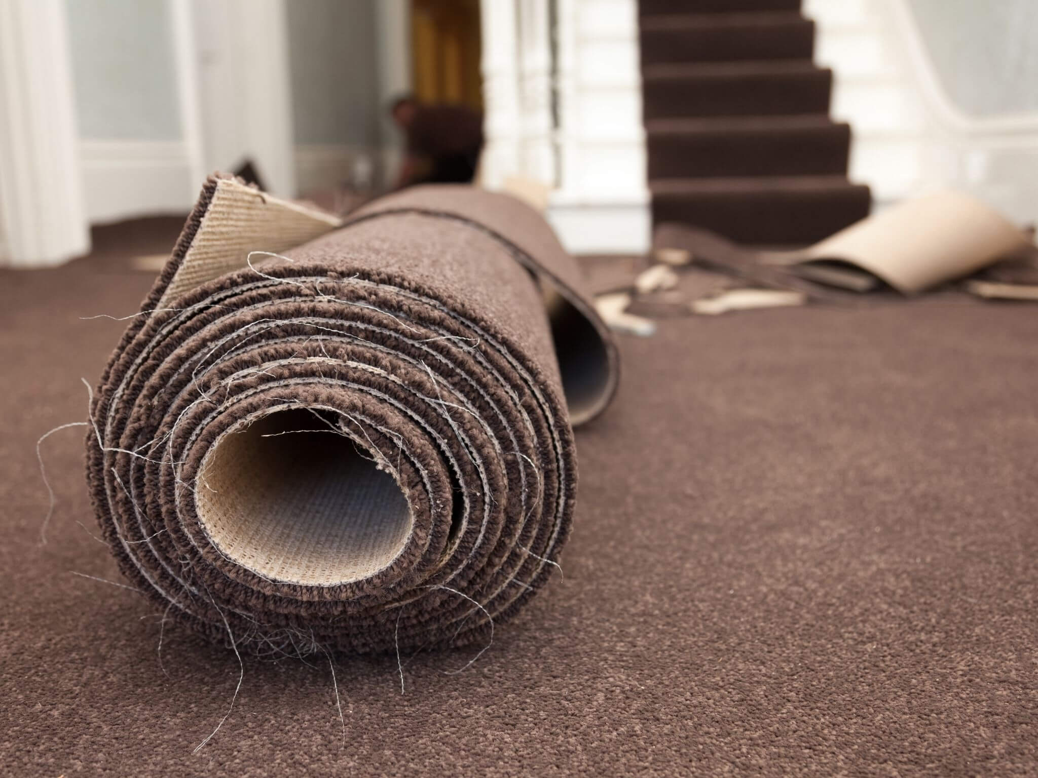 A roll of brown carpet being fitted in a home.