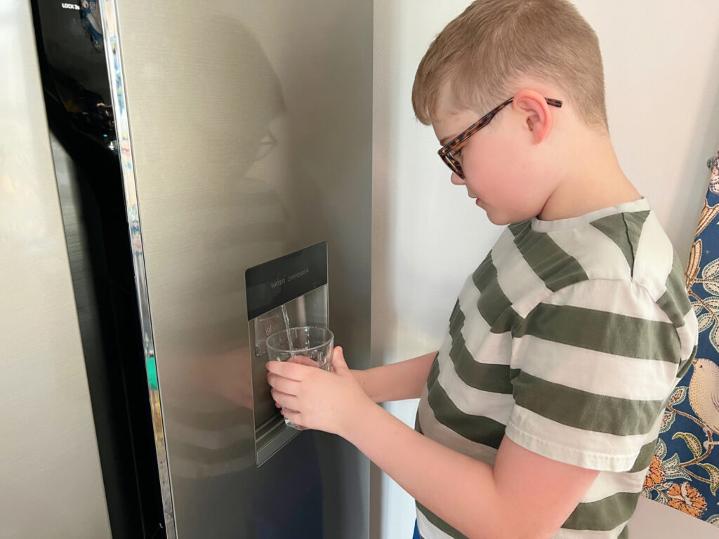 A water dispenser on the front of an American fridge freezer